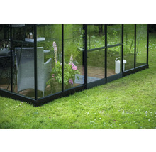 Gewächshaus mit Pflanzkübel, Stuhl und Gießkanne im Garten