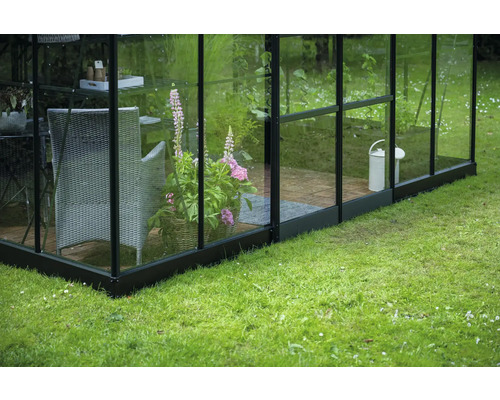 Gewächshaus mit Pflanzkübel, Stuhl und Gießkanne im Garten