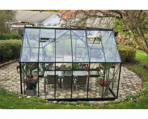 Gewächshaus mit Pflanzen und Sitzgruppe im Garten