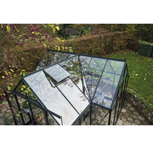 Ein Gewächshaus mit geöffnetem Fenster in einem Garten.