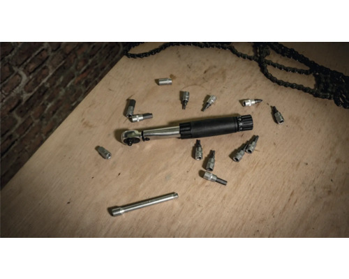 Drehmomentschlüssel mit Steckschlüsseln und Ketten auf einer Holzoberfläche