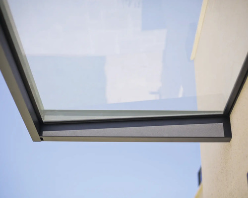 Modernes Vordach aus Glas mit anthrazitfarbenem Metallrahmen an einer Hauswand.