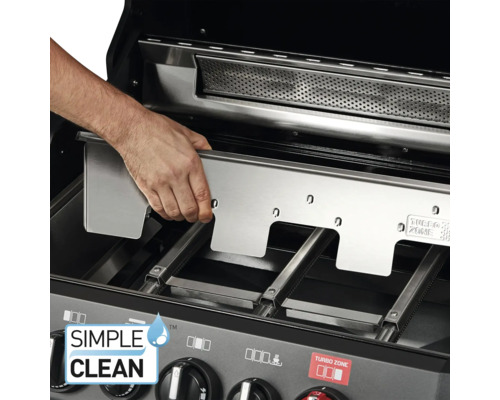 Eine Hand setzt eine Edelstahlplatte in einen Grill ein.