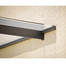 Nahaufnahme einer modernen Glas-Vordach-Halterung mit dunklem Metallrahmen an einer strukturierten Wand.