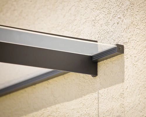 Nahaufnahme einer modernen Glas-Vordach-Halterung mit dunklem Metallrahmen an einer strukturierten Wand.