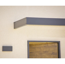 Modernes Vordach in Anthrazit mit integrierter LED Beleuchtung über einer Haustür in Holzoptik und passender Wandleuchte.