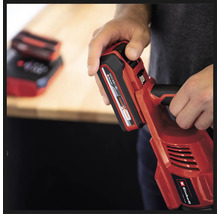 Eine Person hält ein rotes Einhell Akku-Werkzeug mit eingesetztem Akku.