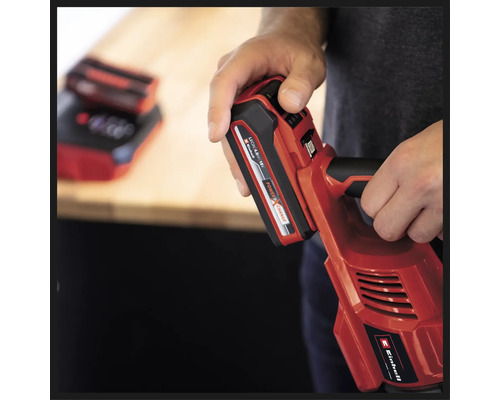 Eine Person hält ein rotes Einhell Akku-Werkzeug mit eingesetztem Akku.