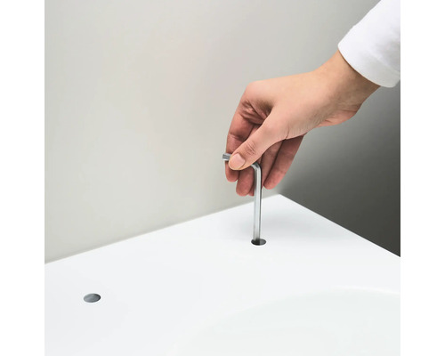 Eine Person führt einen Inbusschlüssel in ein Loch in einer weißen Oberfläche ein