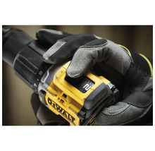 Nahaufnahme einer Person mit Handschuhen, die einen gelben DeWalt Akku-Bohrschrauber hält.