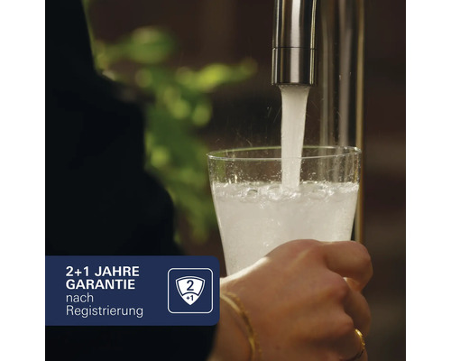 "Ein Glas wird mit Wasser aus einem Wasserhahn gefüllt