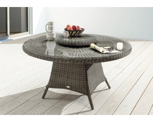 Gartentisch mit Glasplatte und Rattangeflecht auf einer Terrasse dekoriert mit Geschirr und Obst