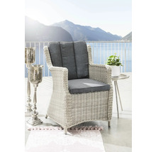 Geflochtener Sessel mit grauen Kissen und Tisch mit Pflanze vor Bergkulisse