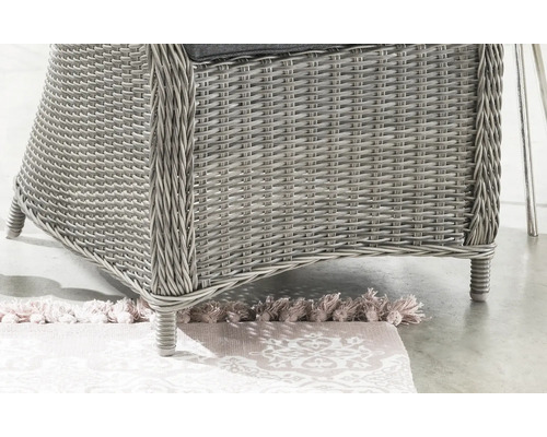 Detailaufnahme eines Gartenstuhls aus Rattan auf einem gemusterten Teppich