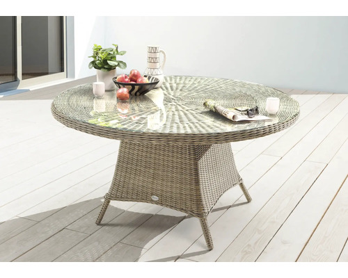 Runder Gartentisch mit Glasplatte und geflochtenem Sockel auf einer Terrasse.