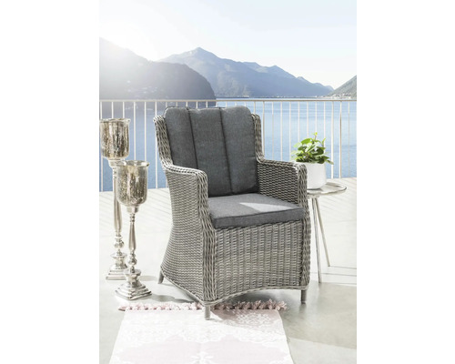 Gartenstuhl mit grauen Polstern, Beistelltisch und Kerzenständer auf einer Terrasse mit Seeblick