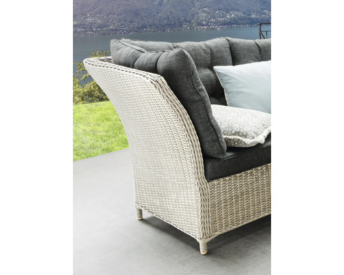 Detailansicht eines Korbstuhls mit grauen Kissen und Blick auf eine malerische Landschaft.