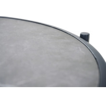 Detailansicht eines runden Tischs mit einer Tischplatte in Steinoptik und einem Metallrahmen.
