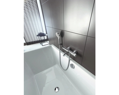 Badezimmer mit weißer Badewanne und Armatur mit Handbrause vor grauer Wand