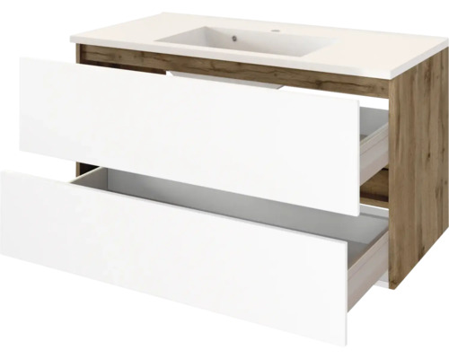 Waschtischunterschrank mit zwei weißen, geöffneten Schubladen, integriertem Waschbecken und Korpus in Holzoptik.