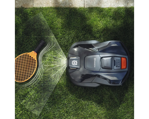 Automatische Rasenmäher bei der Arbeit mit einem Tennisschläger auf dem Rasen