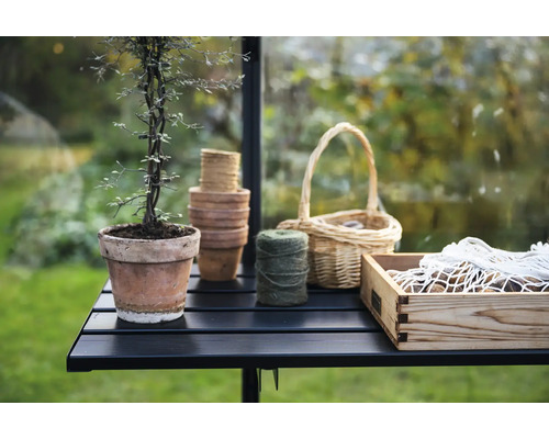 Gartenstillleben mit Pflanze im Topf, Gartentöpfen, Korb, Garn und Holzkiste auf einem Tisch