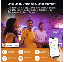 Drei Personen in einem Raum mit bunter Smart-Beleuchtung, gesteuert über eine App auf einem Smartphone für Farbe, Helligkeit und Zeitpläne.
