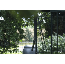 Regenspeicher an einem Gewächshaus mit Bäumen im Hintergrund