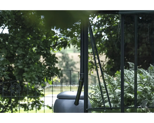 Regenspeicher an einem Gewächshaus mit Bäumen im Hintergrund