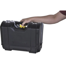 Hand trägt einen Stanley Werkzeugkoffer am Griff und betätigt den gelben Entriegelungsknopf.