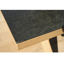 Nahaufnahme einer Tischkante mit dunkler Platte in Steinoptik und Holzgestell.