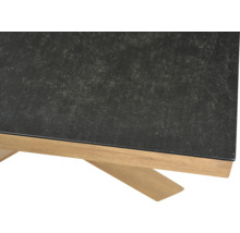 Nahaufnahme eines Tischs mit dunkler strukturierter Tischplatte und einem Untergestell aus hellem Holz.