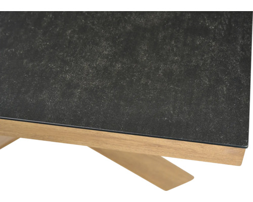 Nahaufnahme eines Tischs mit dunkler strukturierter Tischplatte und einem Untergestell aus hellem Holz.