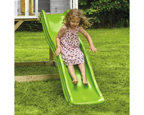 Mädchen rutscht auf einer grünen Kinderrutsche im Garten