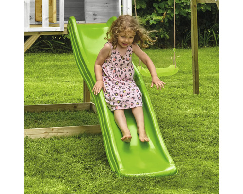 Kind rutscht auf einer grünen Rutsche im Garten.
