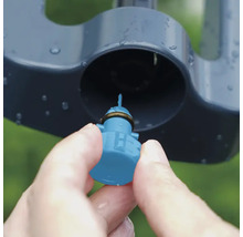 Detailaufnahme einer Hand, die eine Düse in einen Rasensprenger einsetzt.