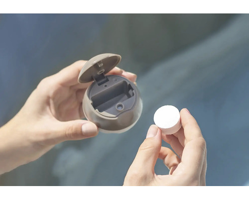 Hände halten eine runde Spenderdose mit geöffnetem Deckel und eine Tablette.