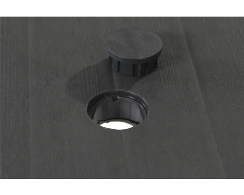 Detailansicht einer runden Öffnung mit passender Abdeckkappe in einer strukturierten Oberfläche.