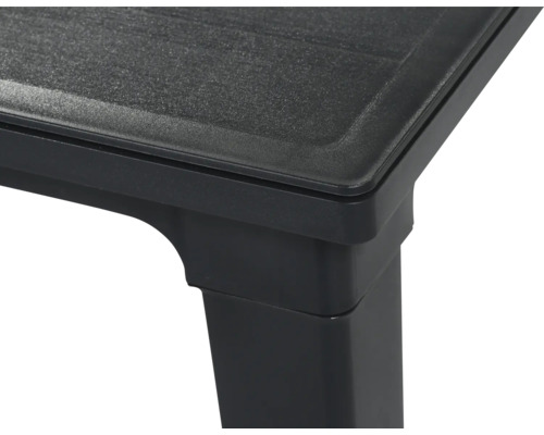 Ecke eines schwarzen Kunststoff-Gartentisches mit strukturierter Tischplatte.