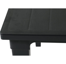 Nahaufnahme der Ecke eines schwarzen Kunststofftisches mit strukturierter Oberfläche in Holzoptik.