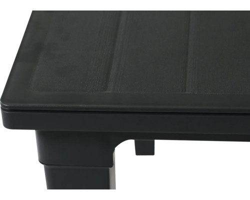 Nahaufnahme der Ecke eines schwarzen Kunststofftisches mit strukturierter Oberfläche in Holzoptik.