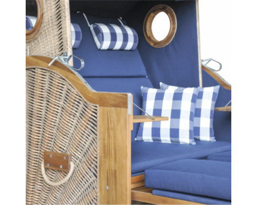 Strandkorb aus Holz und Geflecht mit blauen Polstern, karierten Kissen und Bullaugen.