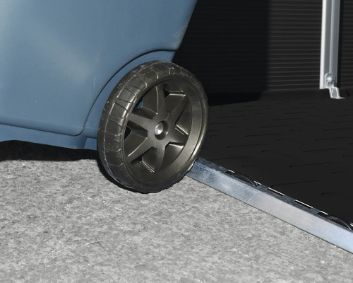 Nahaufnahme eines Rades beim Überfahren einer flachen Metallschwelle an einem Gartenhaus oder einer Aufbewahrungsbox.