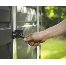 Nahaufnahme einer Hand, die einen schwarzen Metallriegel an einem grauen Gartenhaus mit Aluminiumprofilen betätigt.