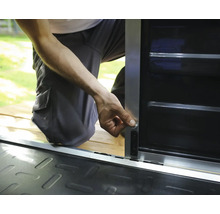 Person montiert einen Riegel an einem Metall-Geräteschrank mit silbernem Rahmen und schwarzen Paneelen.