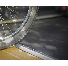 Fahrradreifen auf einer Laderampe oder einem Übergangsprofil aus Metall.