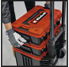 Einhell E-Case System Werkzeugkoffer auf einem Trolley gestapelt, von einer Hand mit Arbeitshandschuh gehalten.