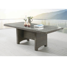 Rechteckiger Gartentisch aus Polyrattan mit Glasplatte auf einer hellen Terrasse mit Aussicht auf Berge.