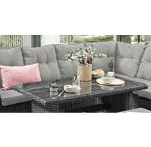 Polyrattan Gartenlounge mit grauem Sofa und Tisch mit Glasplatte, dekoriert mit Geschirr und Blumen auf einer Terrasse.