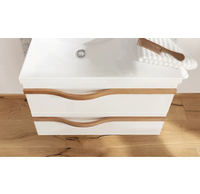 Weißer Badunterschrank mit zwei Schubladen, geschwungenen Holzgriffen und integriertem Waschbecken auf Holzboden.